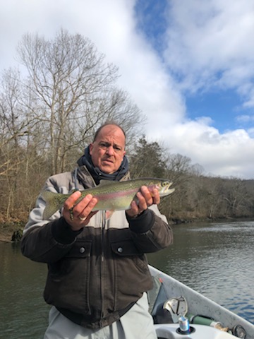 Bobby holding a rainbow trout on the front of a drift boat