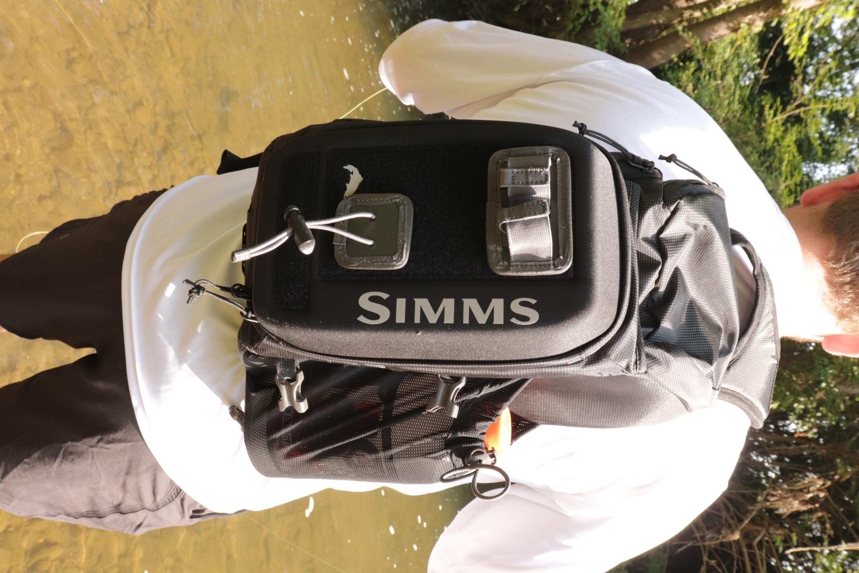 An Angler fishing while whereing the Simms Freestone Sling Pack