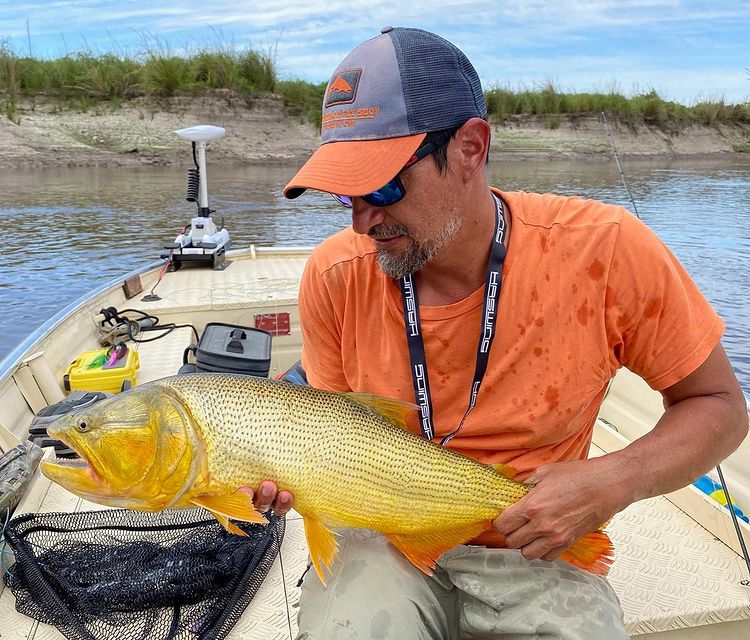 Federico holding a Golden Dorado, on his boat in Argentina