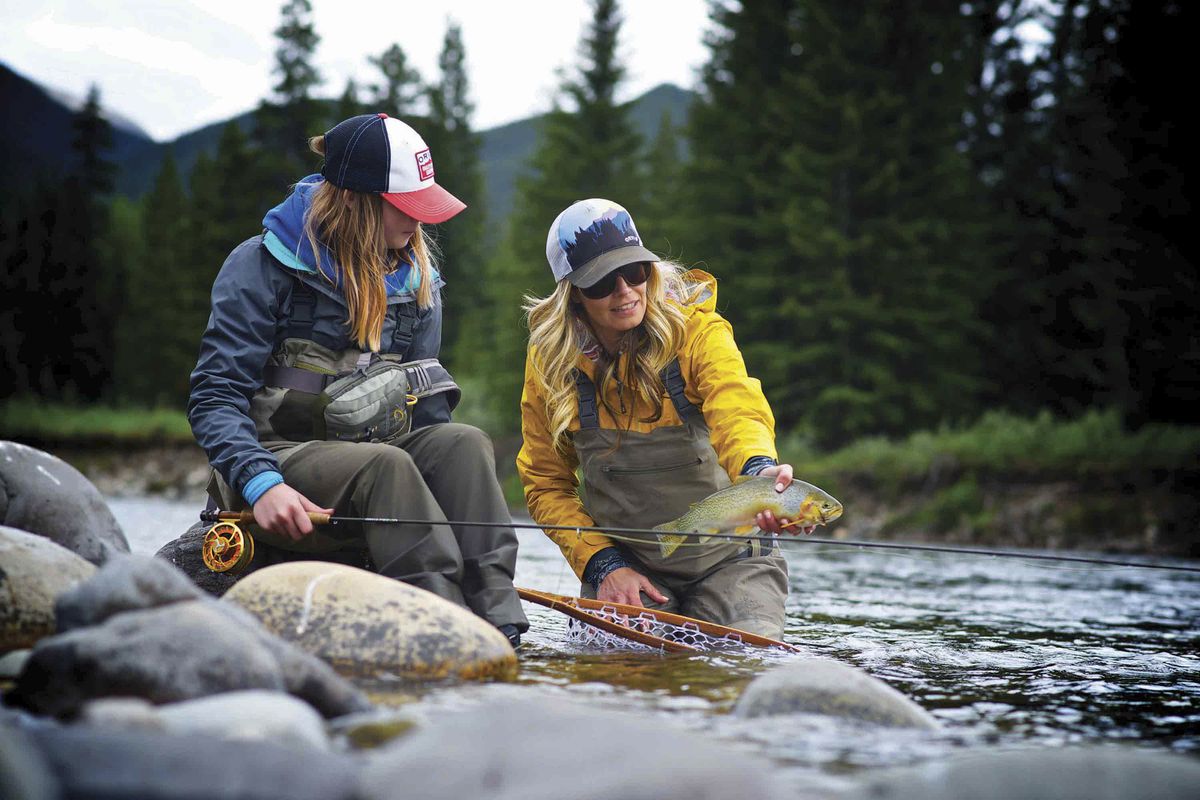Two women catching trout in a river