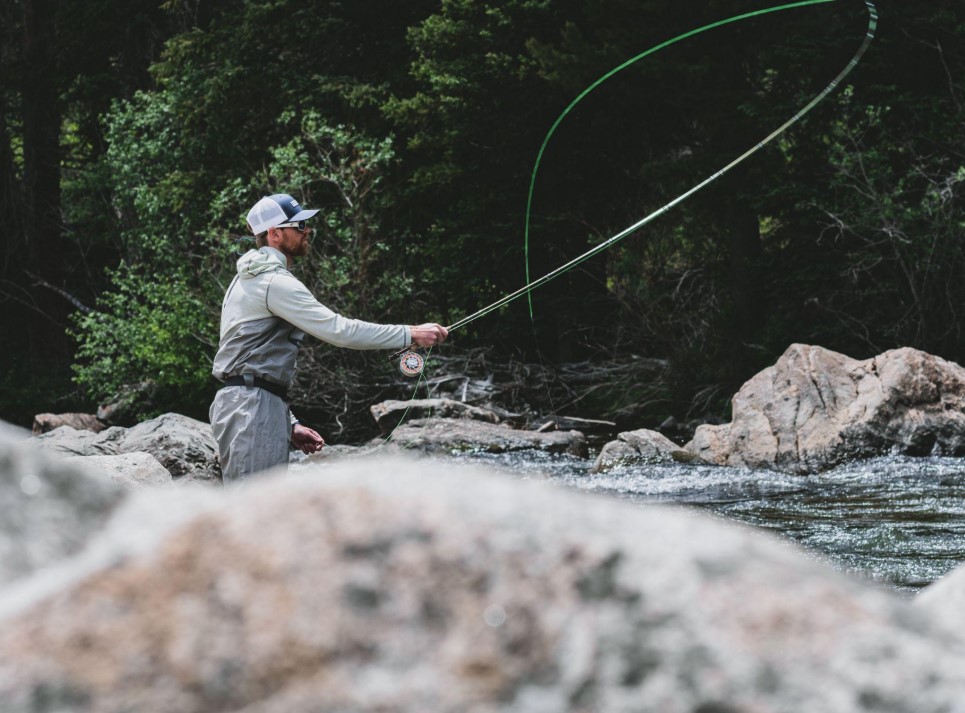 Angler performing a single hand spey cast standing in the middle of a river