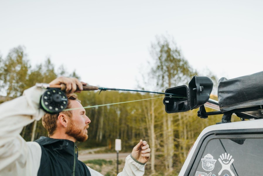 Angler loading a fly rod outfit into a car roof mounted carrier