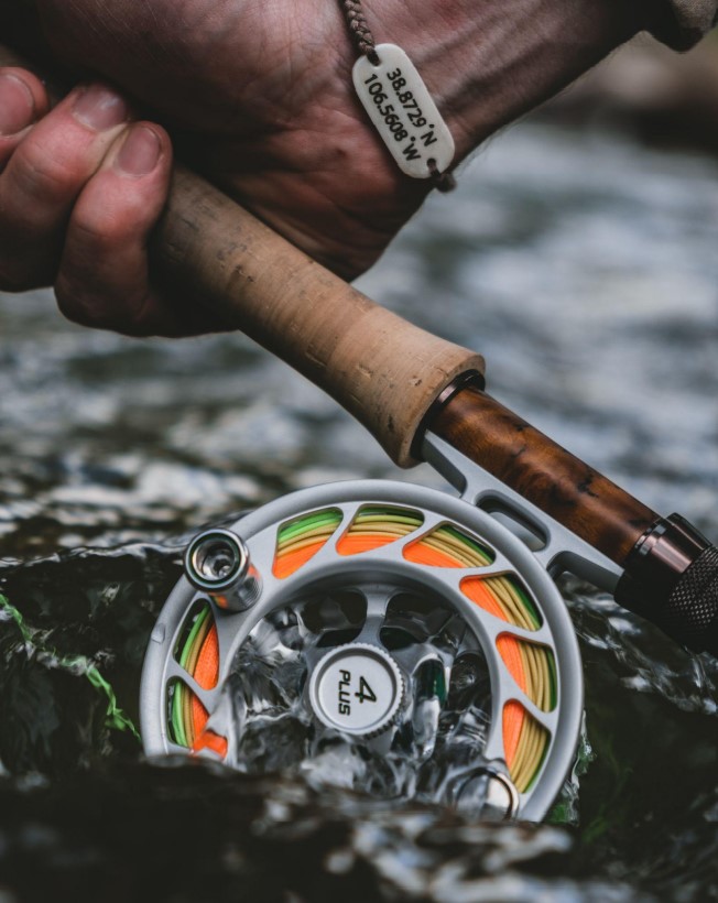 Holding a Fly Rod and Hatch Iconic 4 Plus reel in a fast moving stream