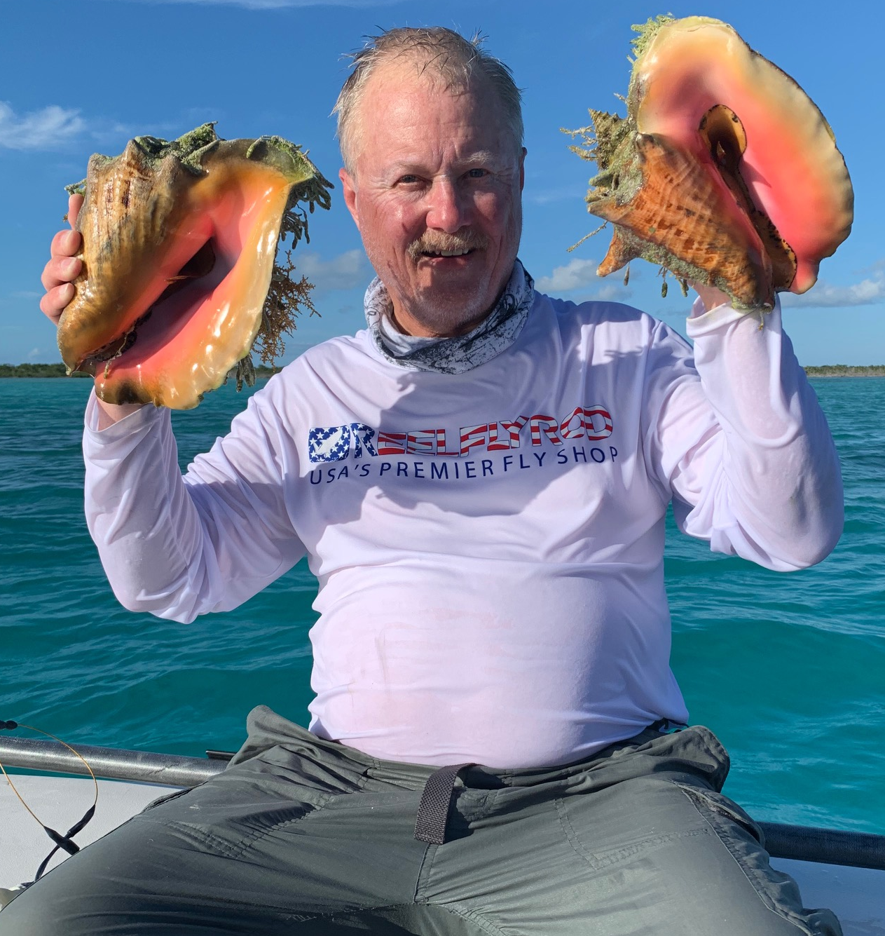 Jon on the boat with two massive conch shells