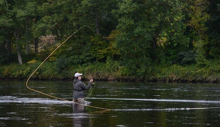 Angler wading in river spey casting with a Switch Rod